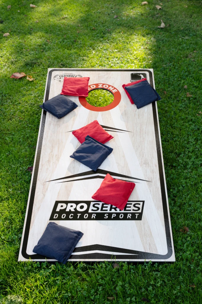 Cornhole Pro Set met rode en navy werpzakken op het gras